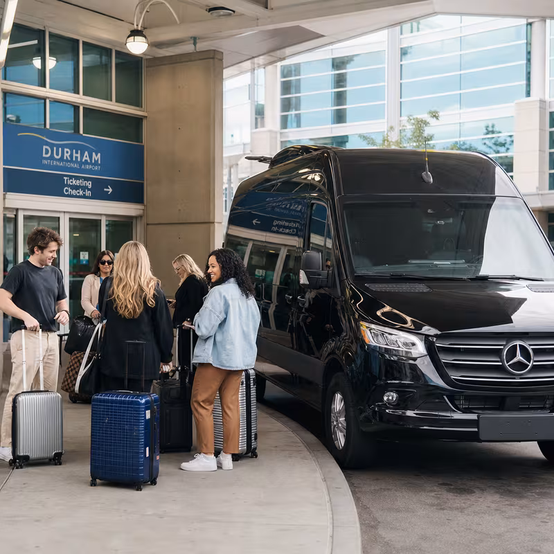 Group boarding a white charter bus for Airport Transportation transportation in Durham