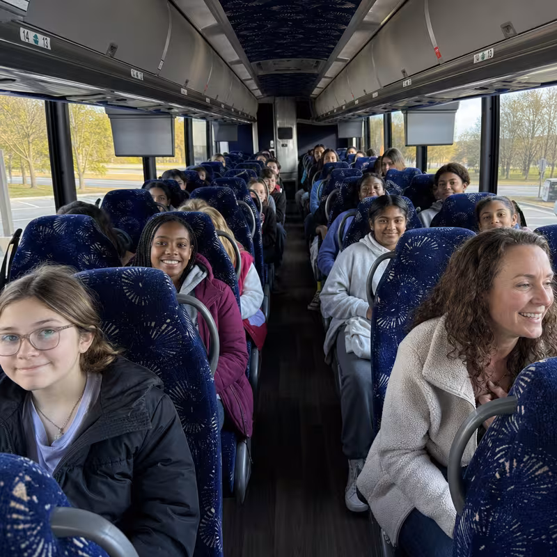 Group boarding a white charter bus for School Transportation transportation in Durham