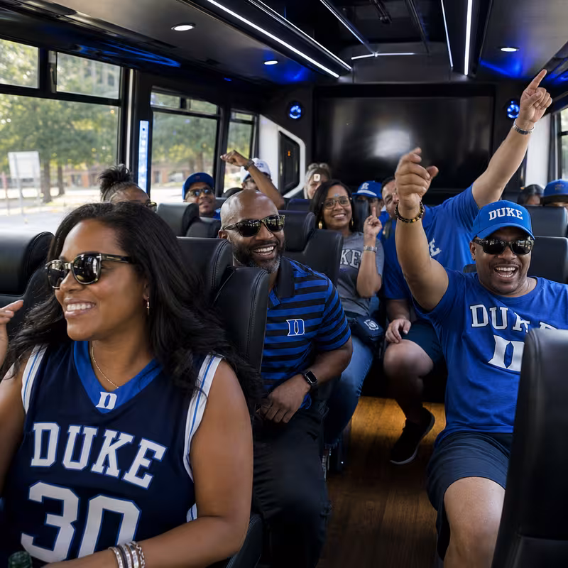 Group boarding a white charter bus for Sporting Event Transportation transportation in Durham